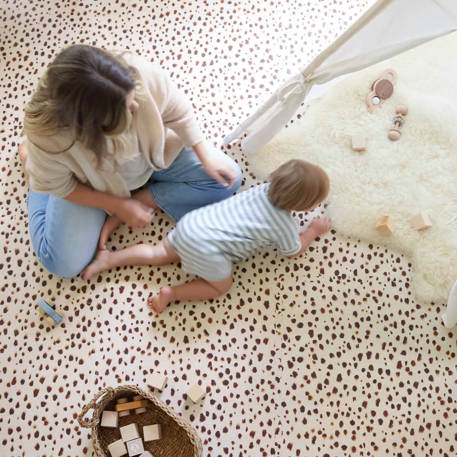 Bobbi Umber brown and beige polka dot little nomad play mat shown with mom and baby on the mat with baby crawling into a play tent