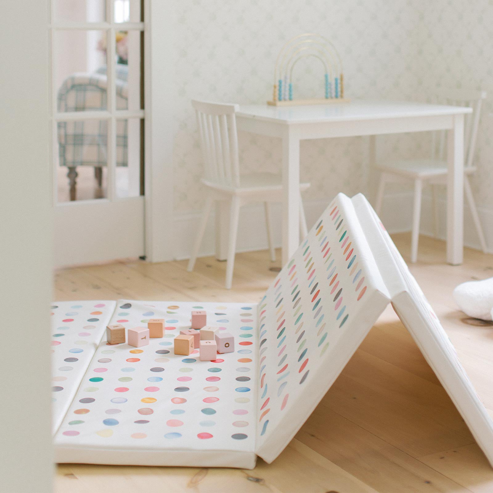 Dottie gloria multi color polkadot print tumbling mat shown in a play room with wooden blocks on the mat and 2 panels folded standing up and 2 panels laying flat