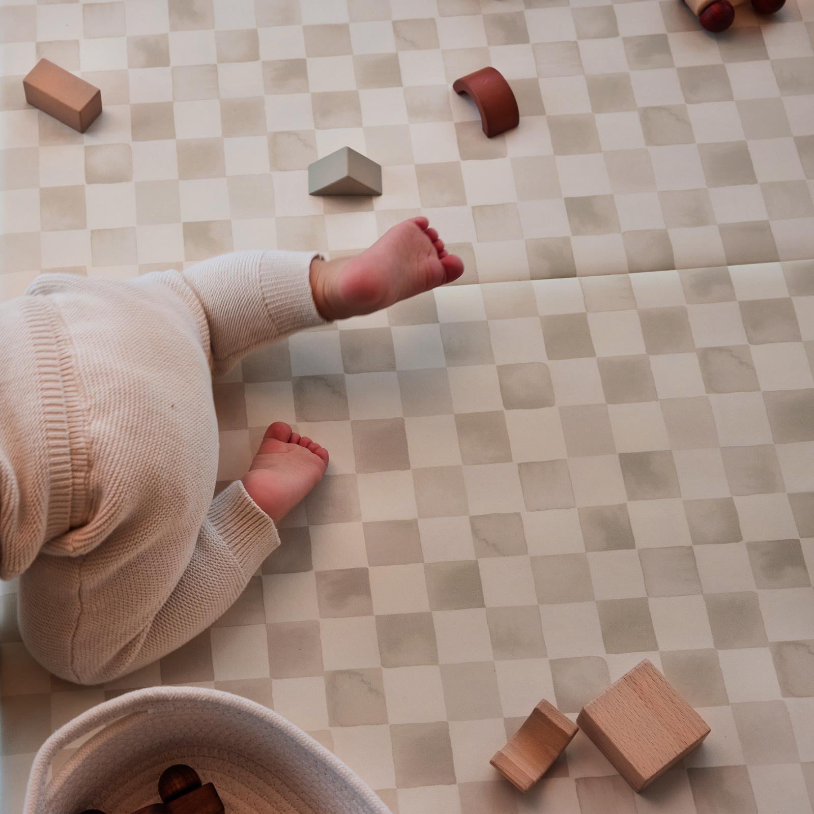 Almond neutral checker print tumbling mat with baby crawling by and wooden blocks laid on them mat