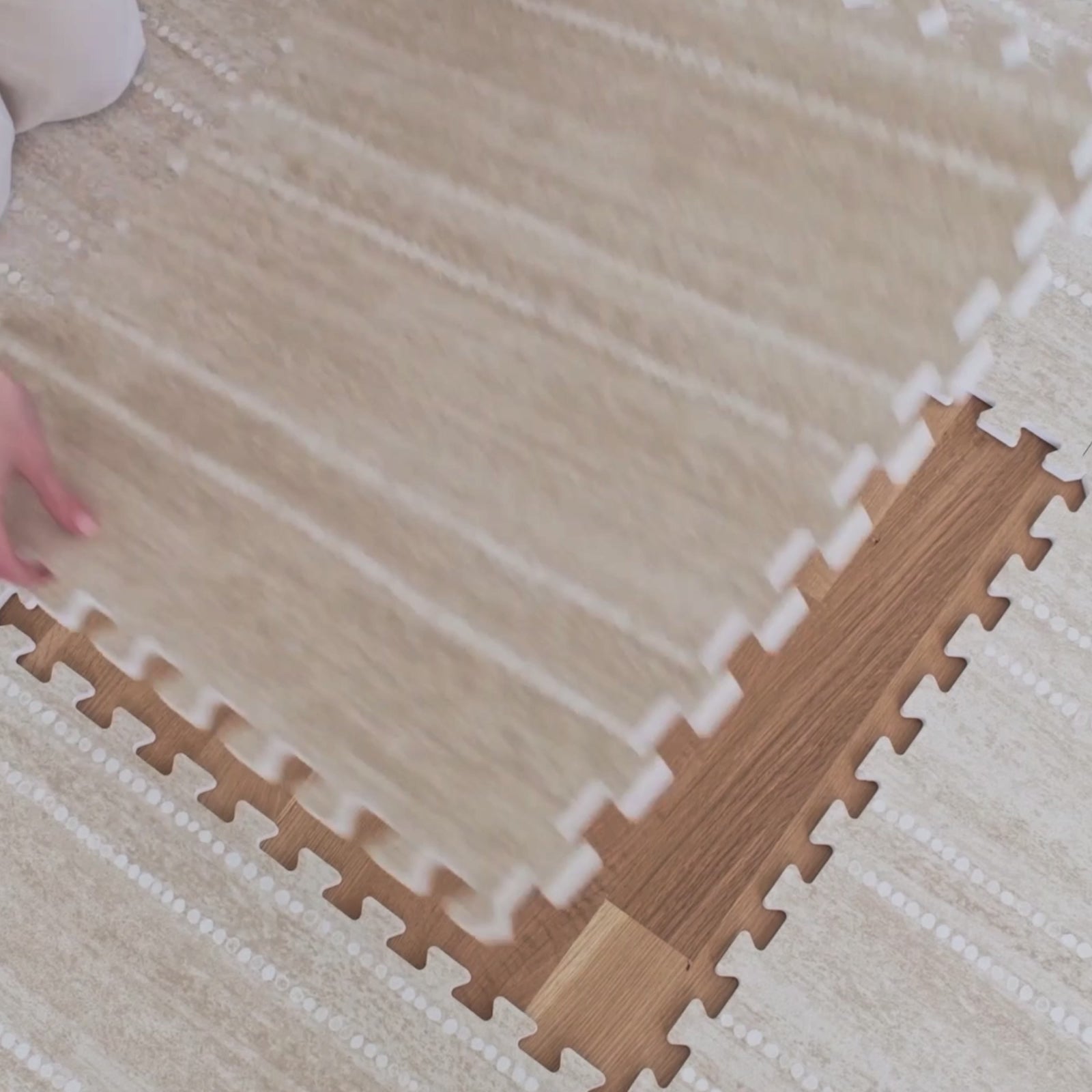 Video of the Aspen toast neutral minimal stripe little nomad play mat with a tile being put in place and toddler playing on the mat in a living room