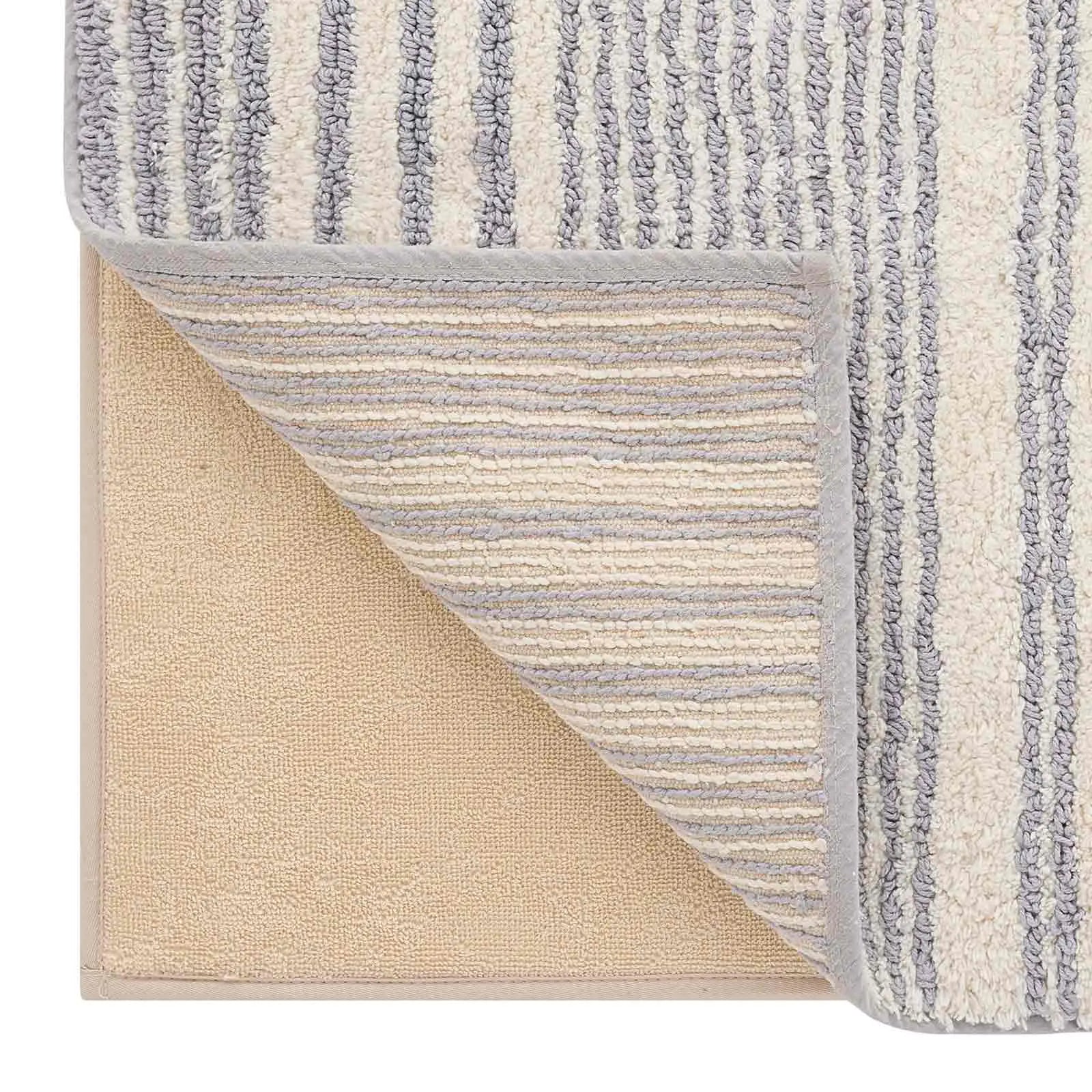 Coastal Nantucket blue and white stripe bath mat close up of a lifted corner of the mat showing the liner beneath